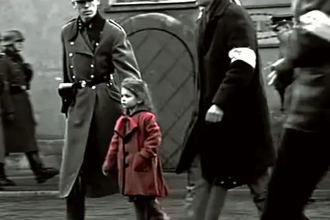 Mała dziewczynka w czerwonym płaszczyku idzie obok żołnierzy.