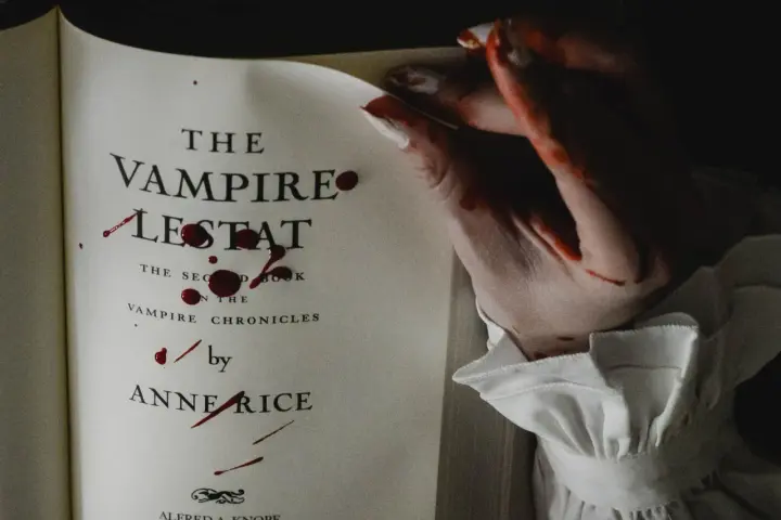 Książki o wampirach dla młodzieży, jak "Wampir Lestat" Anne Rice, z krwawymi śladami na stronach i dłoni.